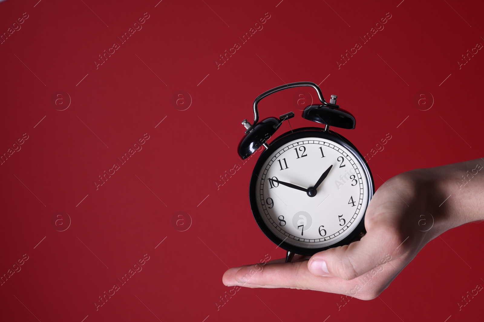 Photo of Man with alarm clock on red background, closeup. Space for text