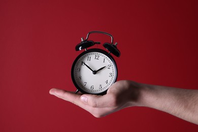 Photo of Man with alarm clock on red background, closeup