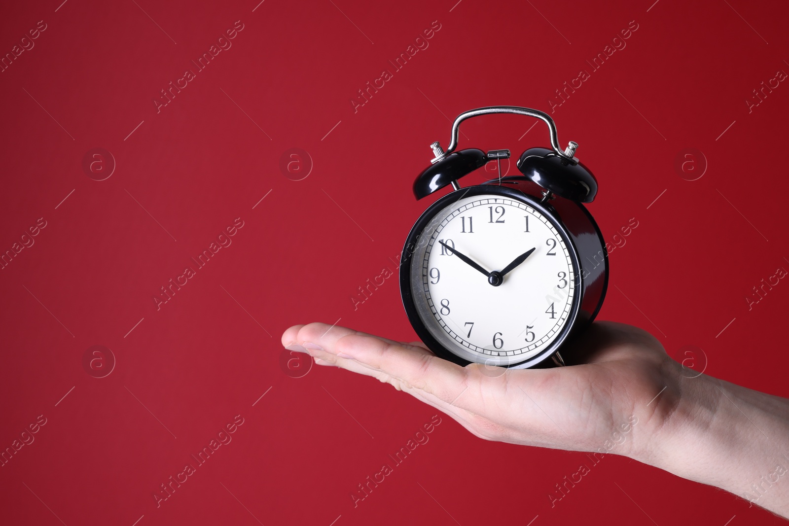 Photo of Man with alarm clock on red background, closeup. Space for text