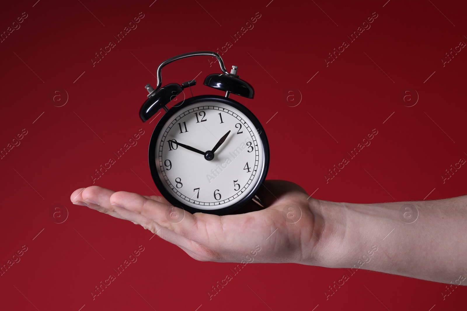 Photo of Man with alarm clock on red background, closeup