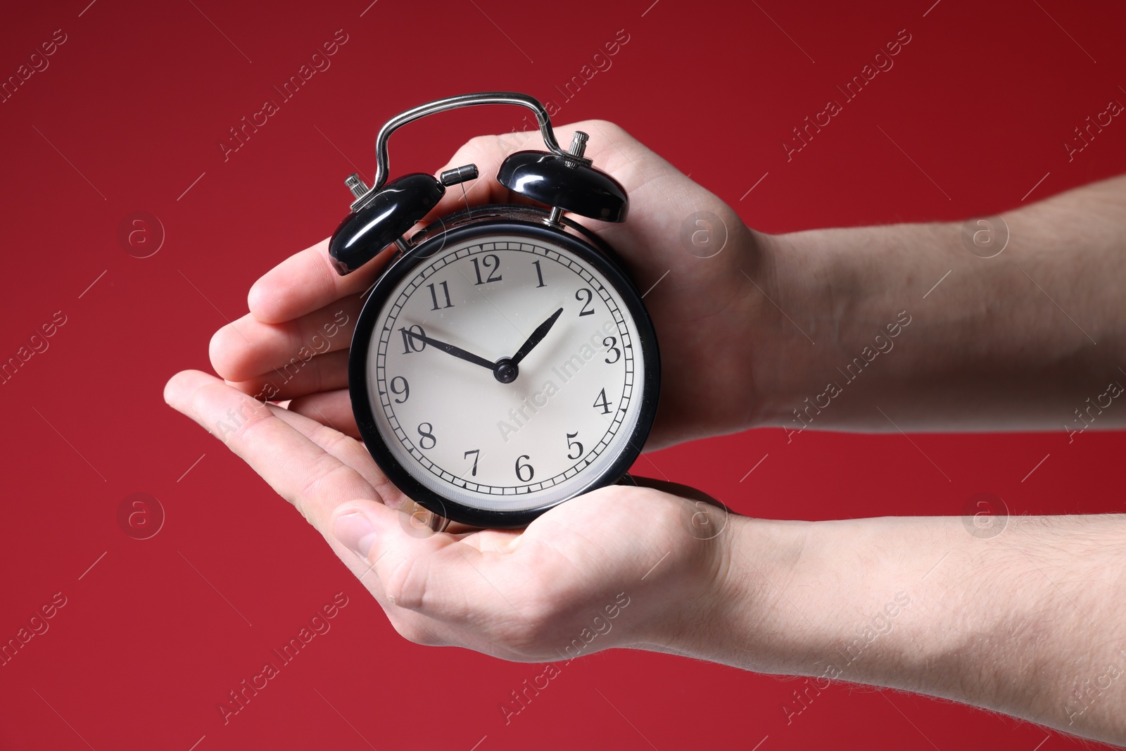 Photo of Man with alarm clock on red background, closeup