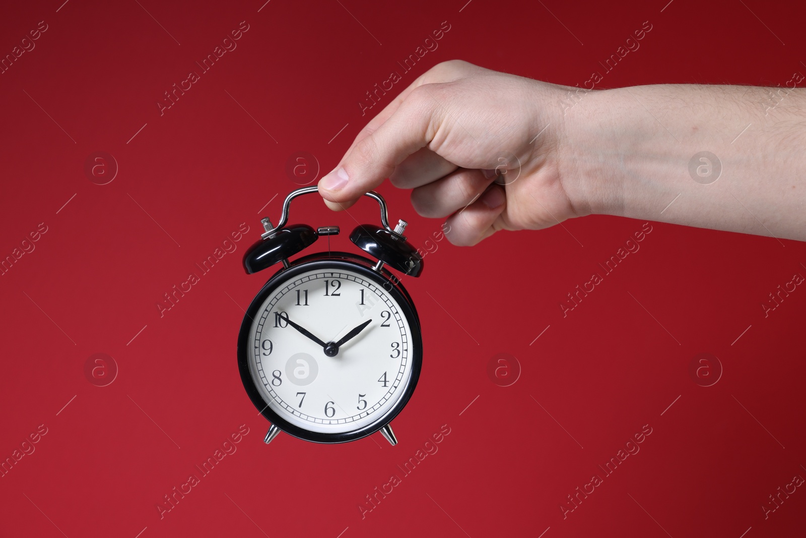 Photo of Man with alarm clock on red background, closeup. Space for text