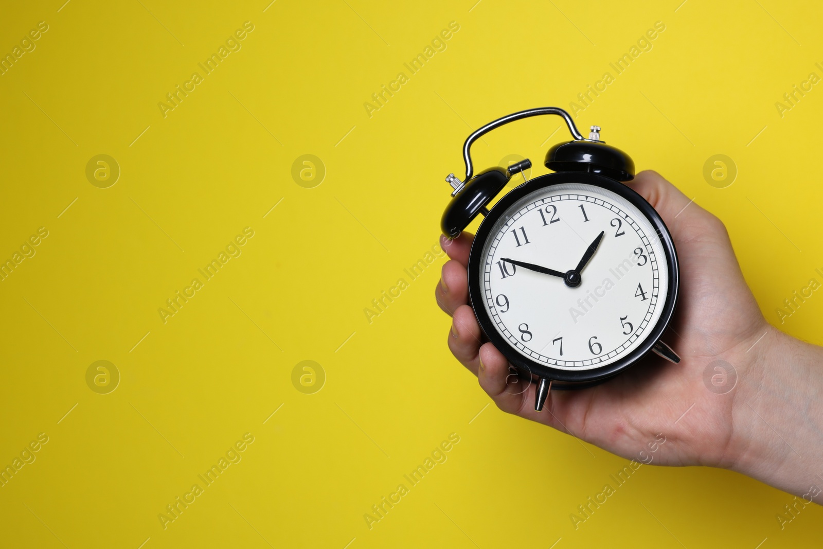 Photo of Man with alarm clock on yellow background, closeup. Space for text