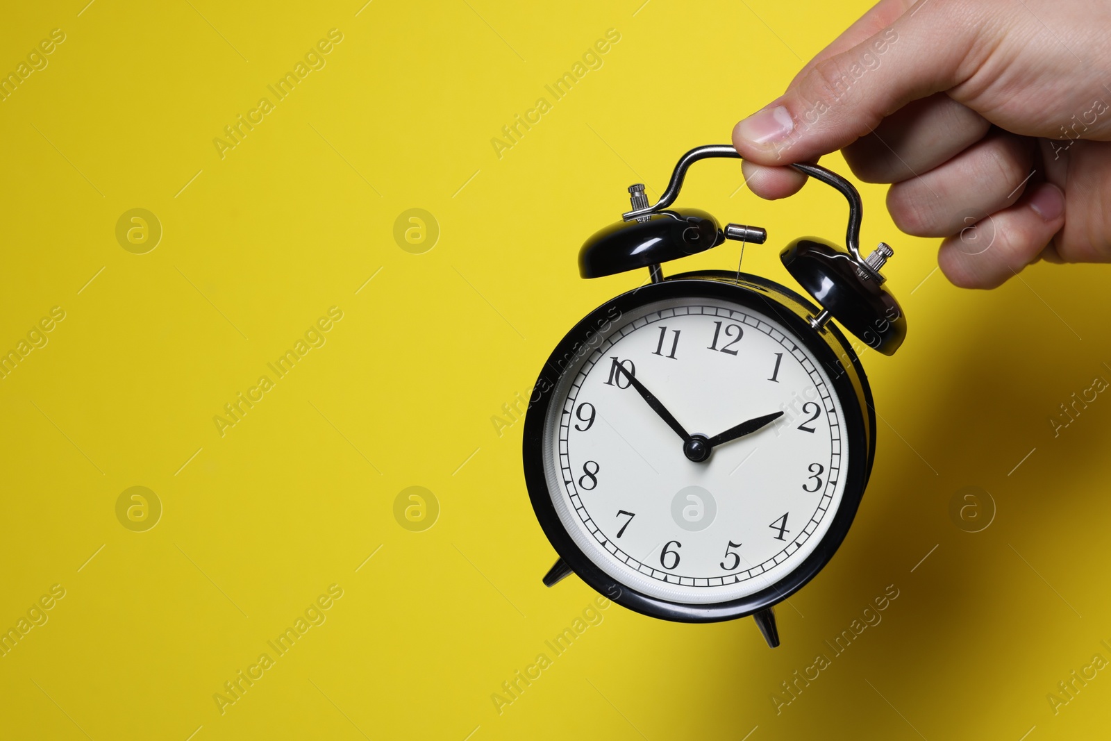 Photo of Man with alarm clock on yellow background, closeup. Space for text