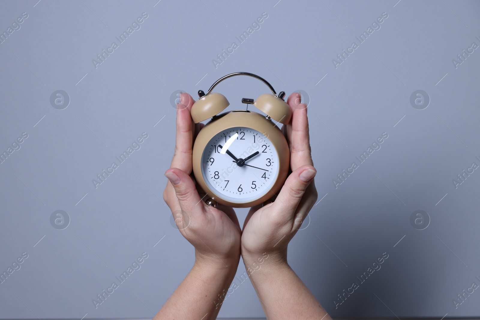 Photo of Woman with alarm clock on grey background, closeup