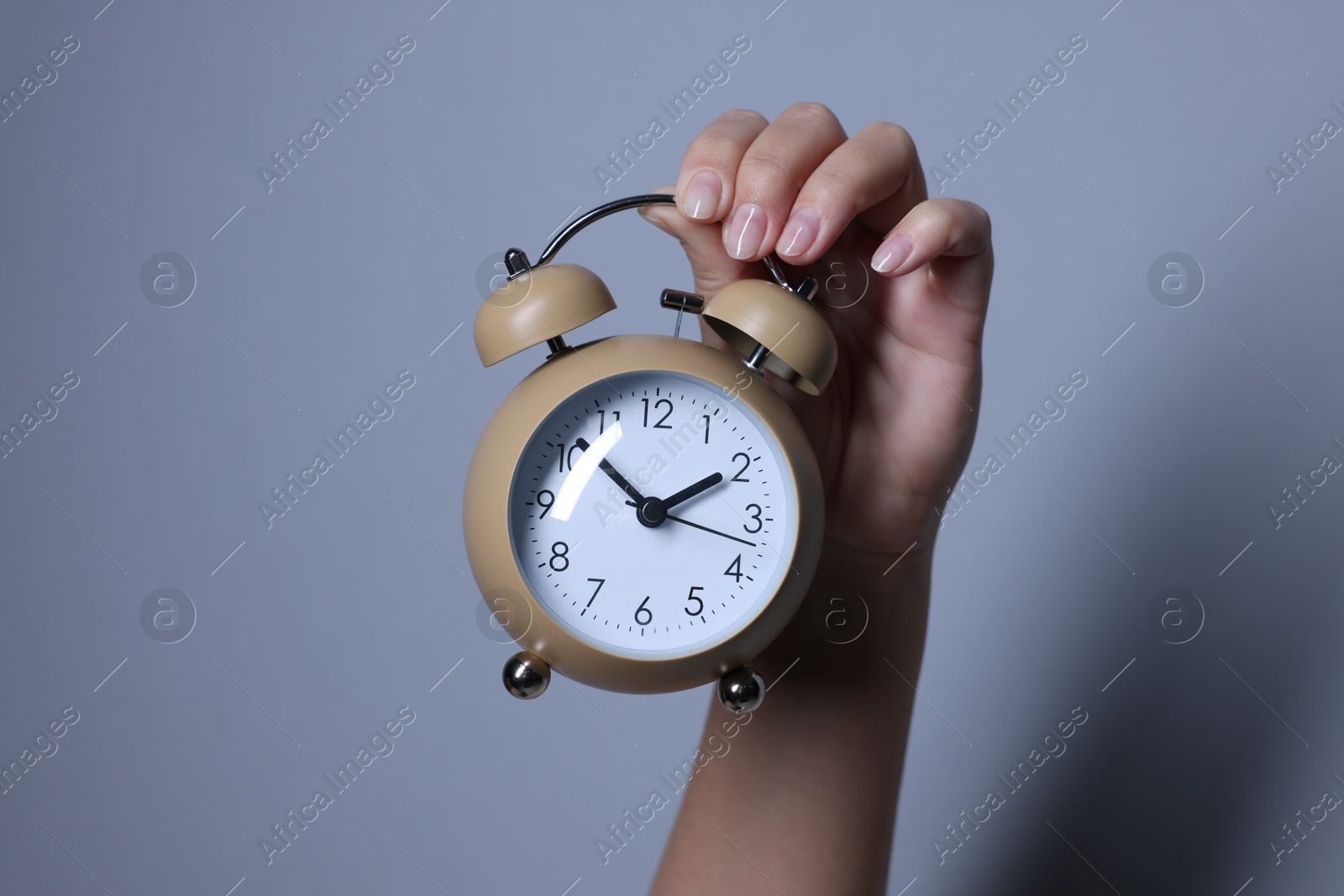 Photo of Woman with alarm clock on grey background, closeup