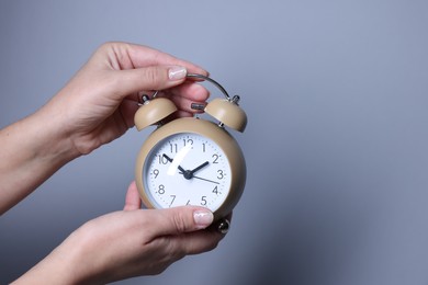 Photo of Woman with alarm clock on grey background, closeup. Space for text