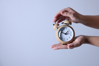 Photo of Woman with alarm clock on grey background, closeup. Space for text