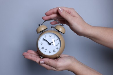 Photo of Woman with alarm clock on grey background, closeup