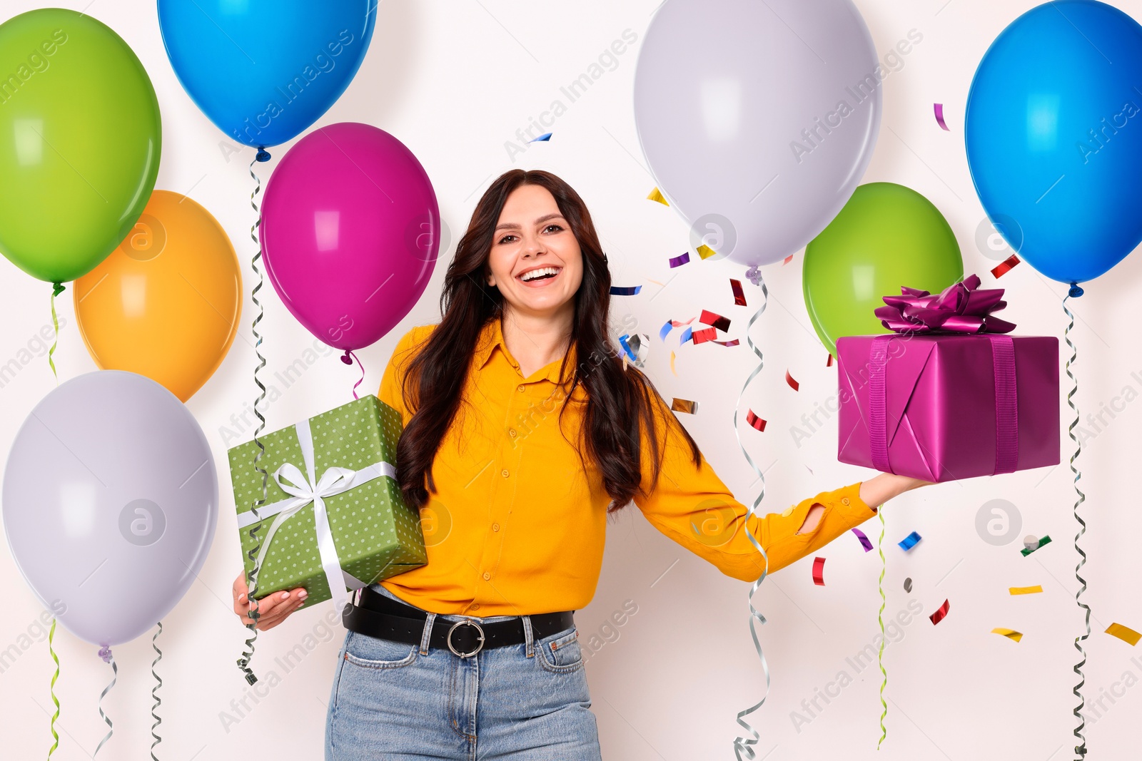 Image of Happy woman with gift boxes and bright balloons on white background. Surprise party