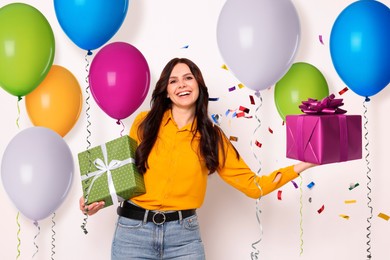 Image of Happy woman with gift boxes and bright balloons on white background. Surprise party