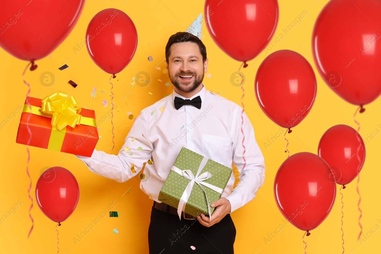 Image of Happy man with gift boxes and red balloons on orange background. Surprise party