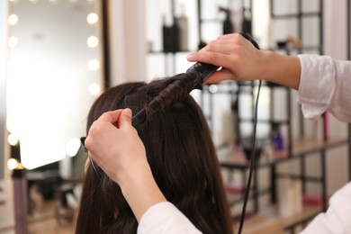 Photo of Stylist working with client in salon, making hairstyle