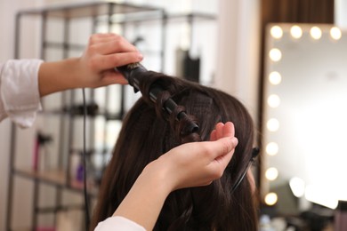 Photo of Stylist working with client in salon, making hairstyle