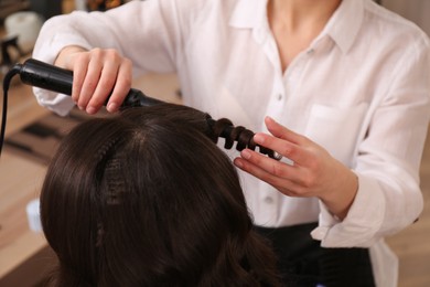 Stylist working with client in salon, making hairstyle