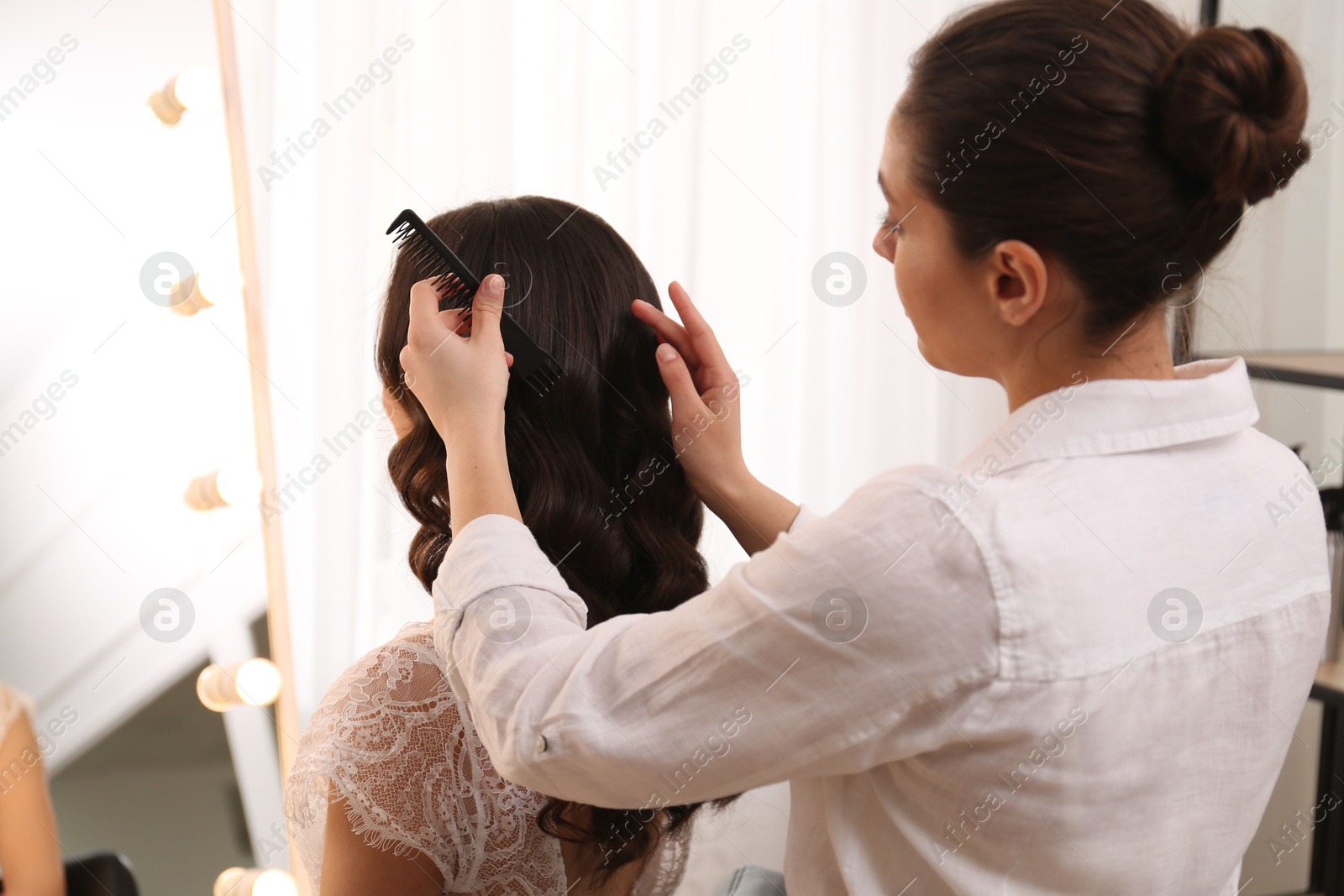 Photo of Stylist working with client in salon, making wedding hairstyle