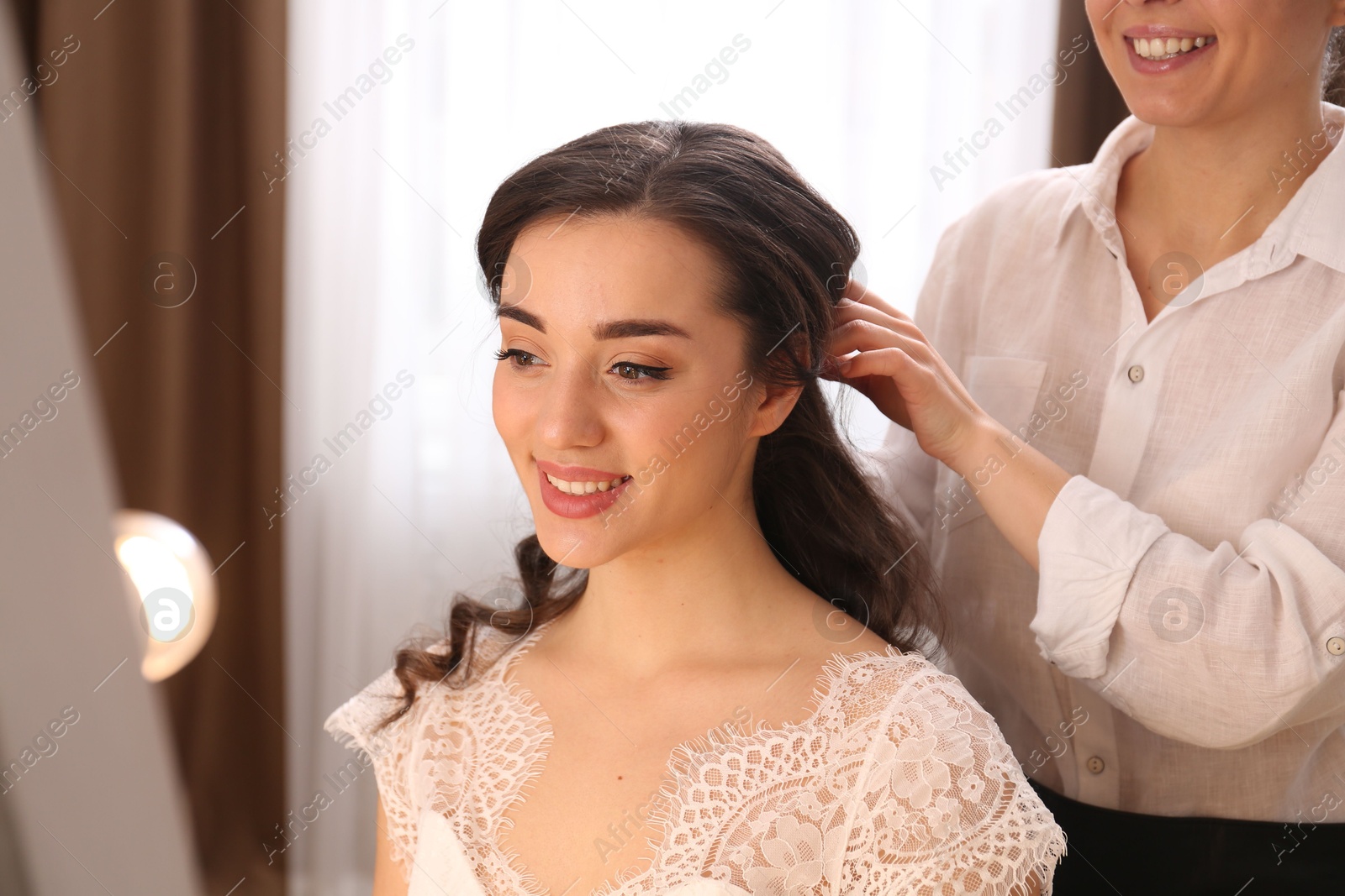 Photo of Stylist working with client in salon, making wedding hairstyle