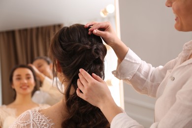 Photo of Stylist working with client in salon, making wedding hairstyle