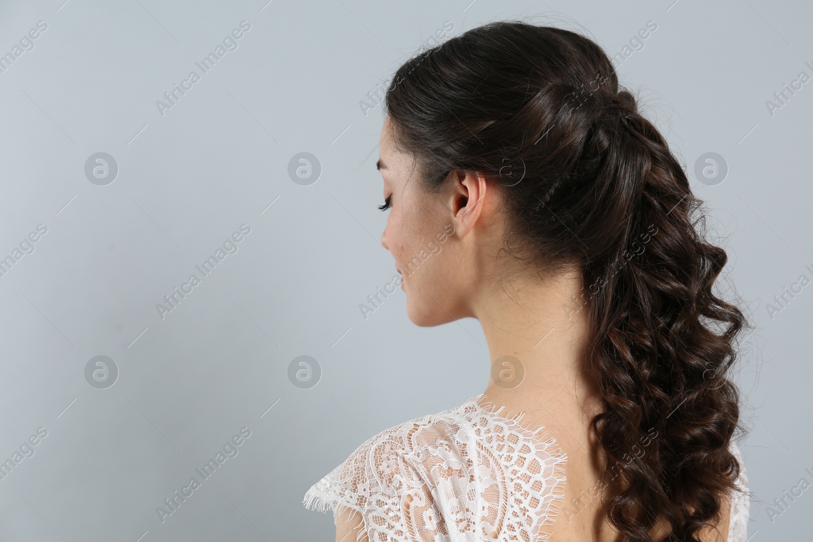 Photo of Young bride with beautiful wedding hairstyle on light grey background. Space for text