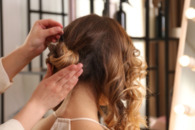 Photo of Stylist working with client in salon, making hairstyle