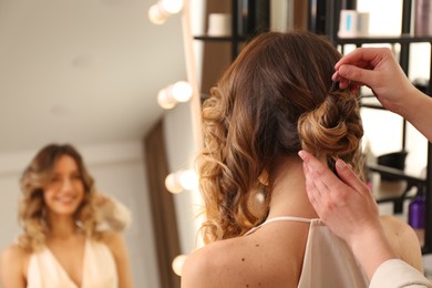 Photo of Stylist working with client in salon, making hairstyle