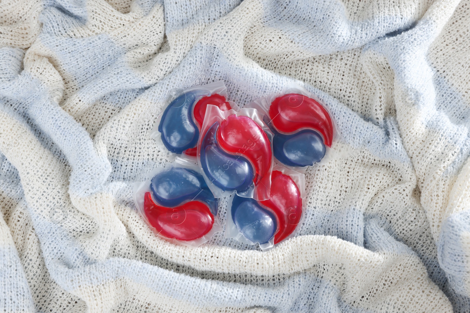 Photo of Laundry detergent capsules on color fabric, top view