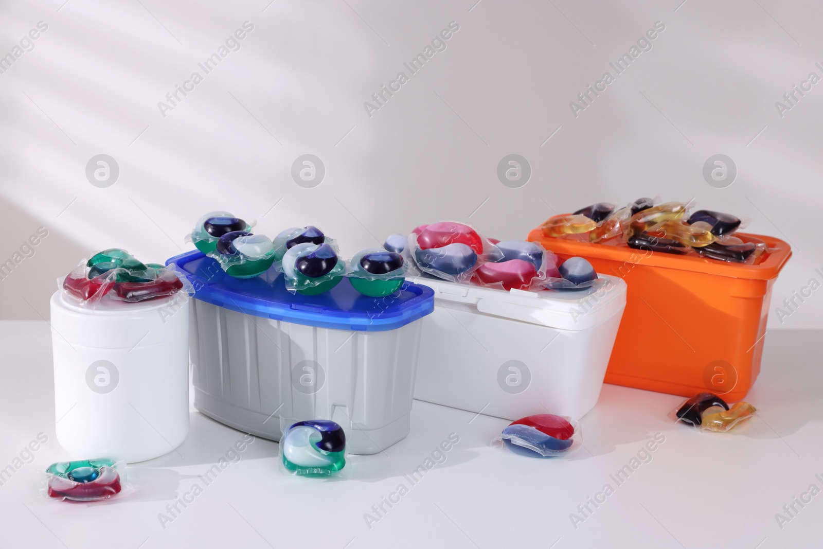 Photo of Containers with different laundry detergent capsules on white background