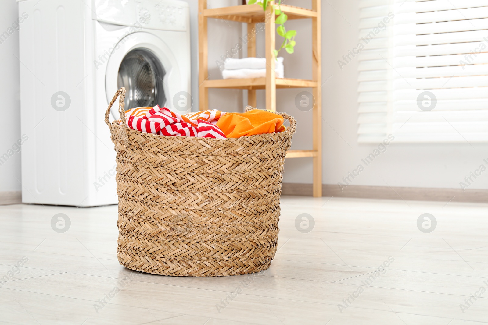 Photo of Wicker basket full of laundry in bathroom, space for text