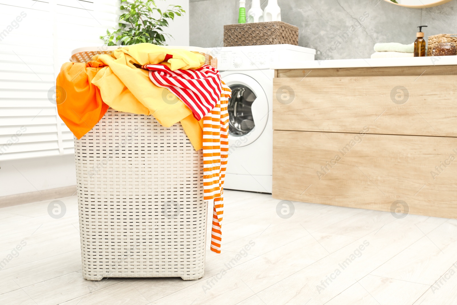 Photo of Wicker basket full of laundry in bathroom