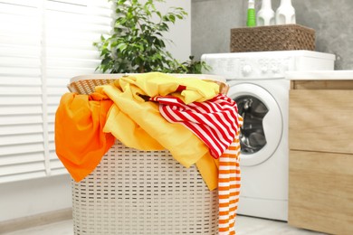 Photo of Wicker basket full of laundry in bathroom