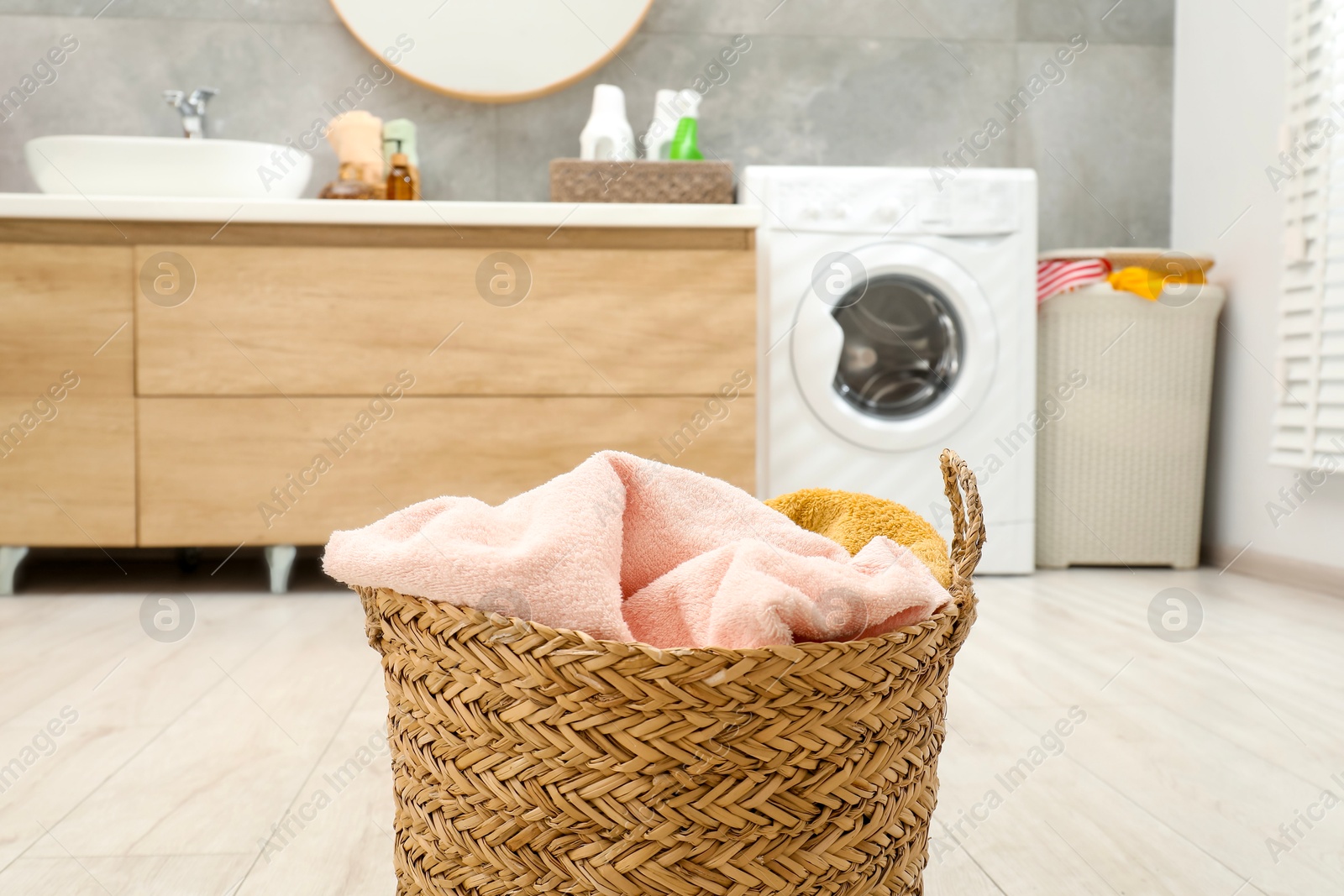 Photo of Wicker basket full of laundry in bathroom