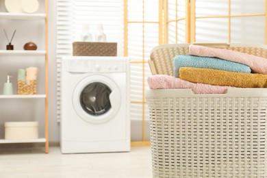 Photo of Wicker basket full of laundry in bathroom