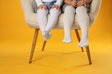 Photo of Kids wearing tights in armchair on orange background, closeup