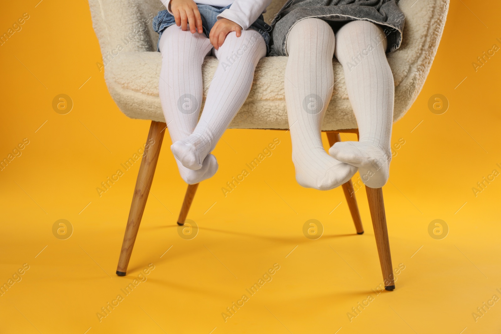 Photo of Kids wearing tights in armchair on orange background, closeup