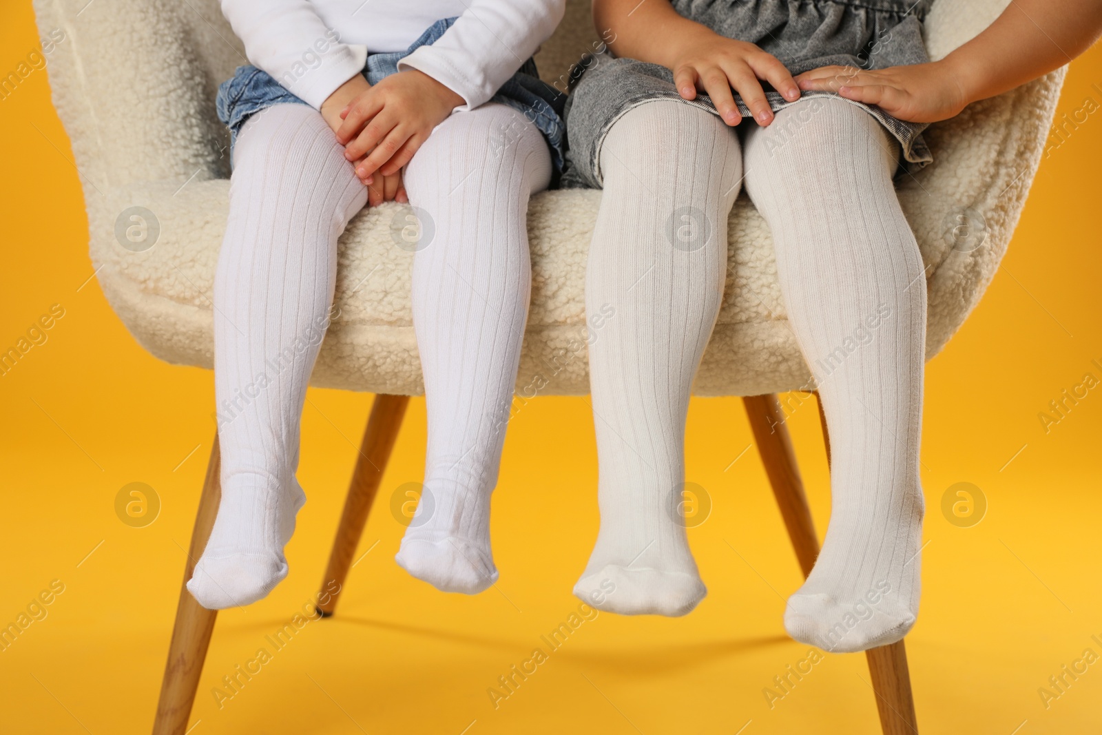 Photo of Kids wearing tights in armchair on orange background, closeup