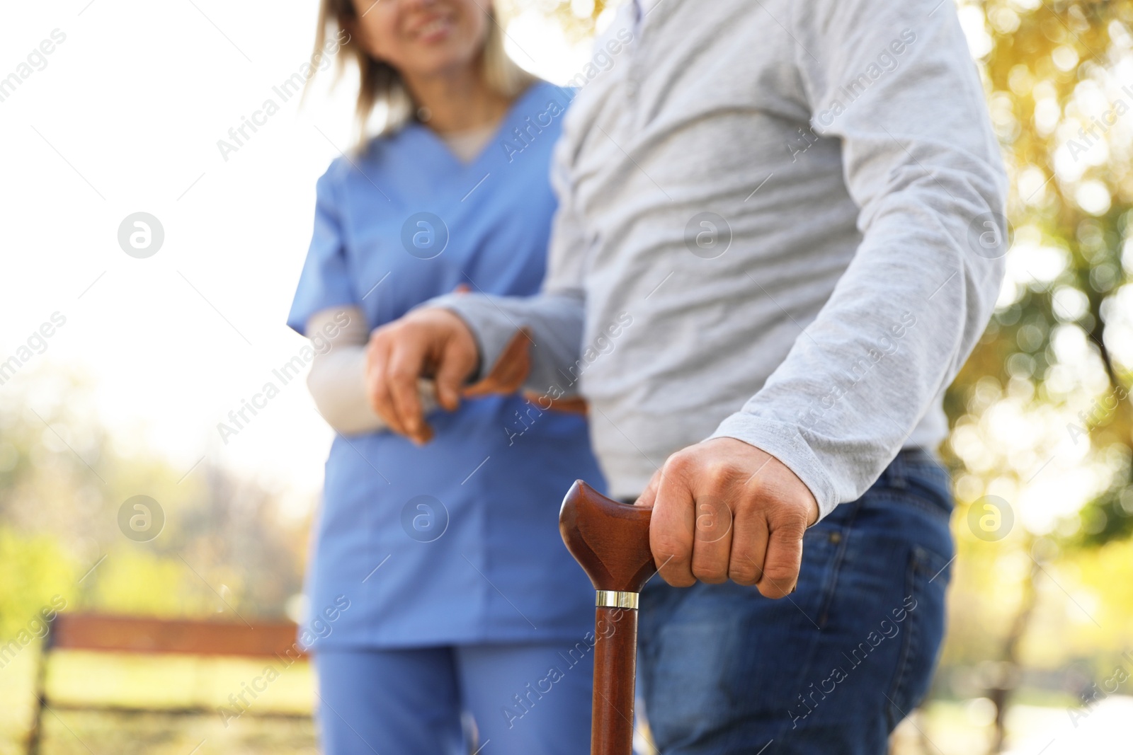 Photo of Caregiver assisting senior man in park, closeup. Home health care service