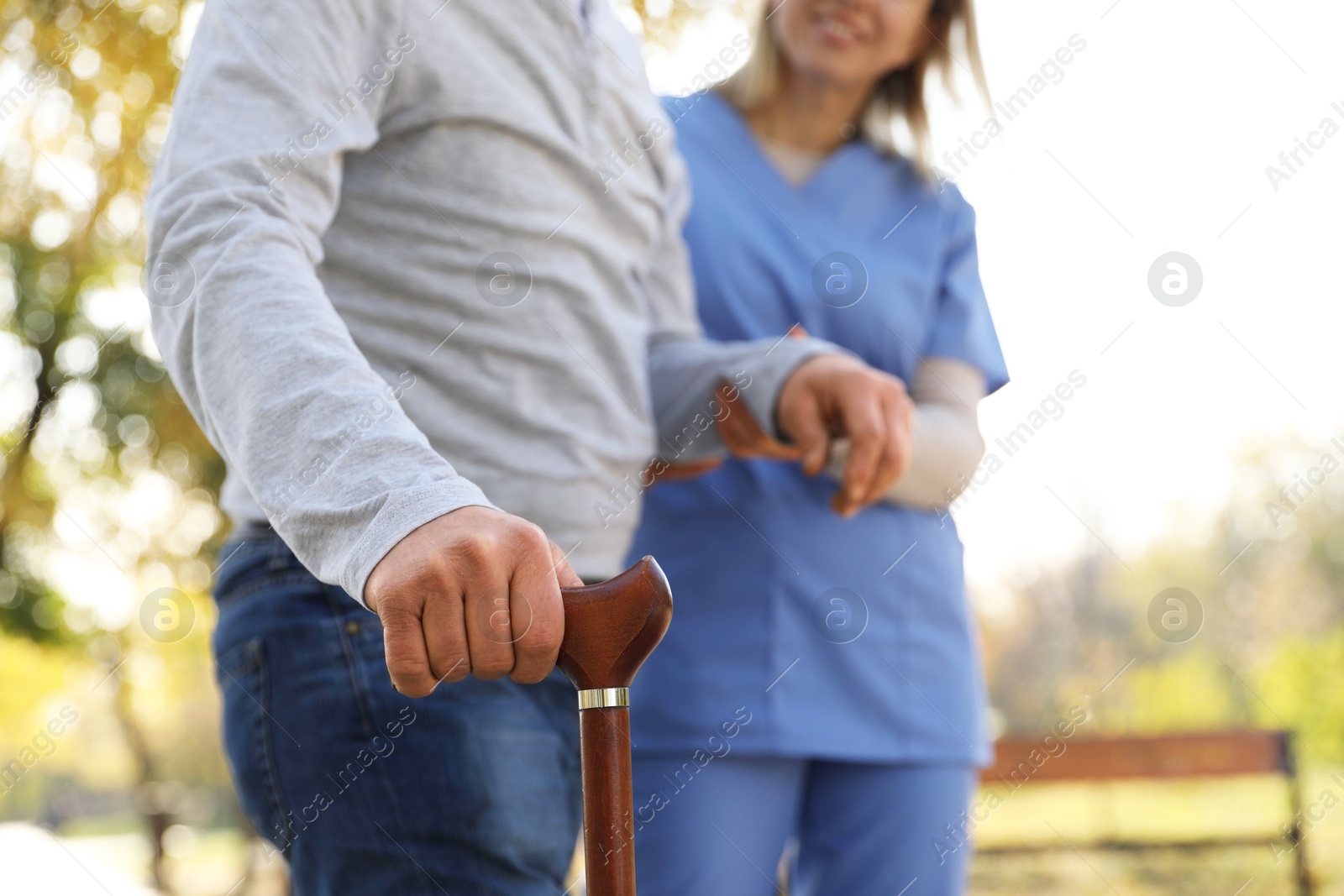 Photo of Caregiver assisting senior man in park, closeup. Home health care service