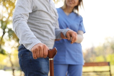 Photo of Caregiver assisting senior man in park, closeup. Home health care service