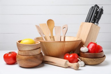 Photo of Dishware, cooking utensils with vegetables and lemon on white table