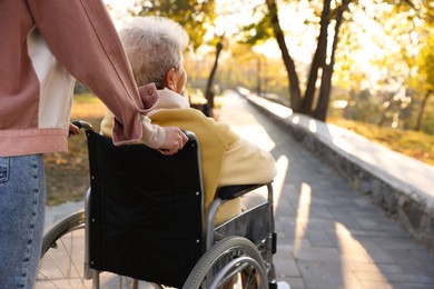 Photo of Caregiver with elderly woman in wheelchair at park, closeup