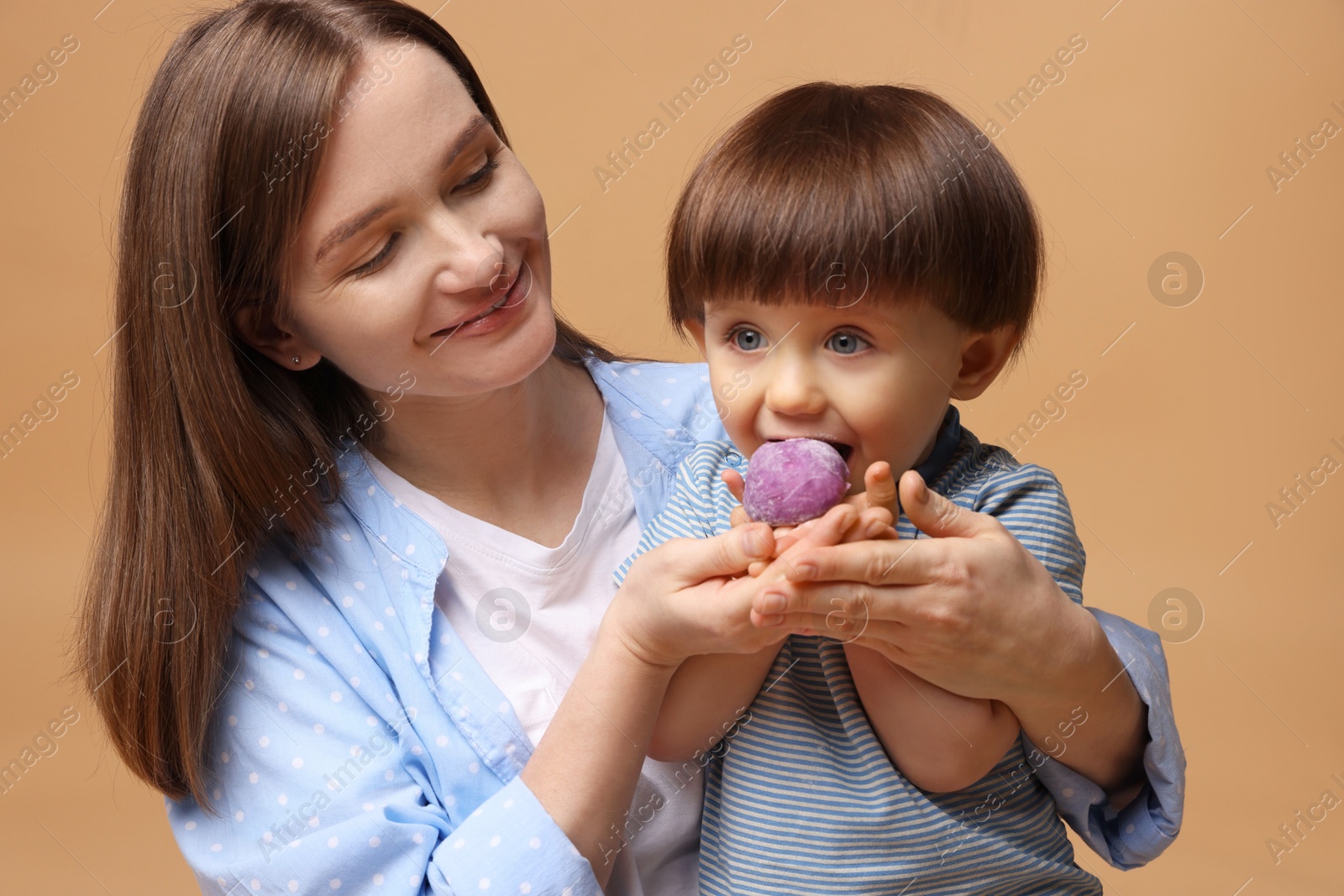 Photo of Mother and baby eating tasty mochi on brown background