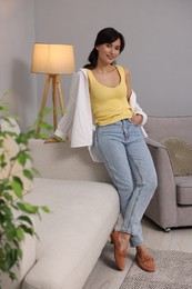 Photo of Beautiful young woman near light grey wall indoors