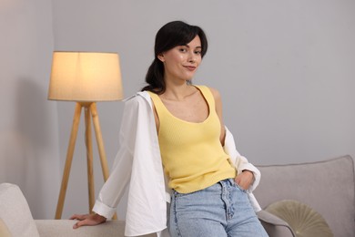 Photo of Portrait of beautiful young woman near light grey wall indoors