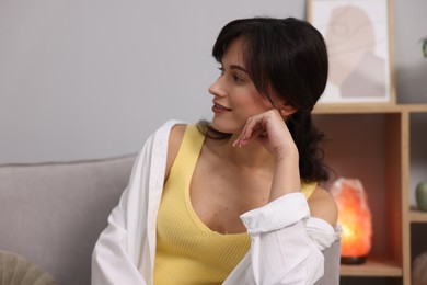 Portrait of beautiful young woman near light grey wall indoors