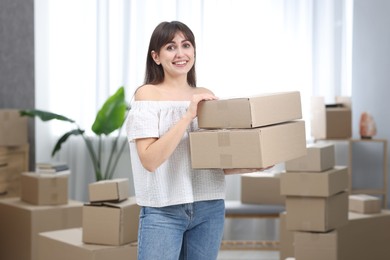 Photo of Moving day. Happy woman with cardboard boxes in her new home