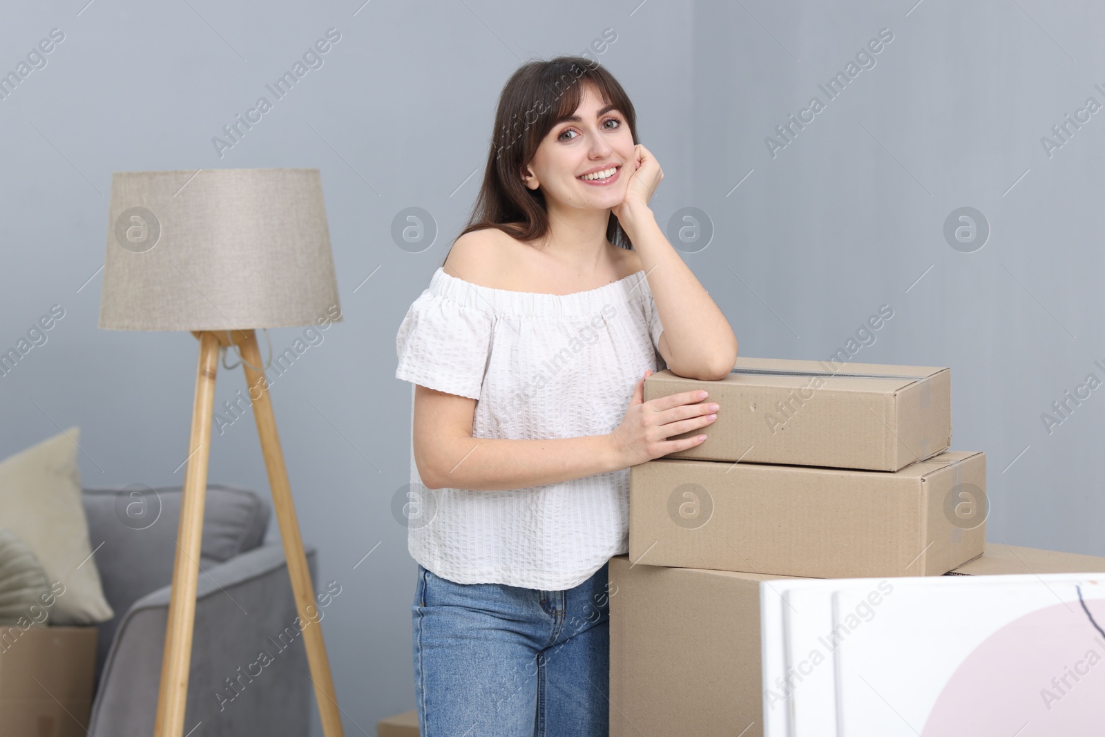 Photo of Moving day. Happy woman with her belongings in new home