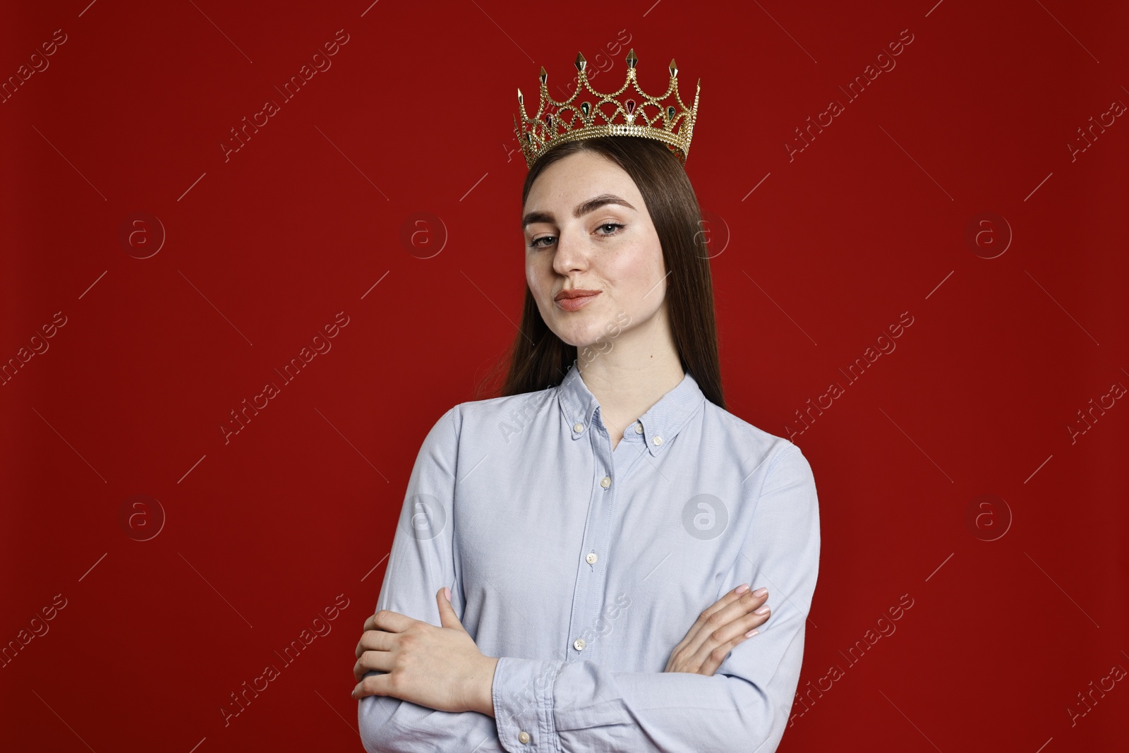 Photo of Woman in elegant crown on dark red background