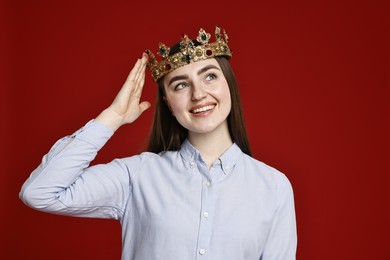 Photo of Smiling woman in elegant crown on dark red background