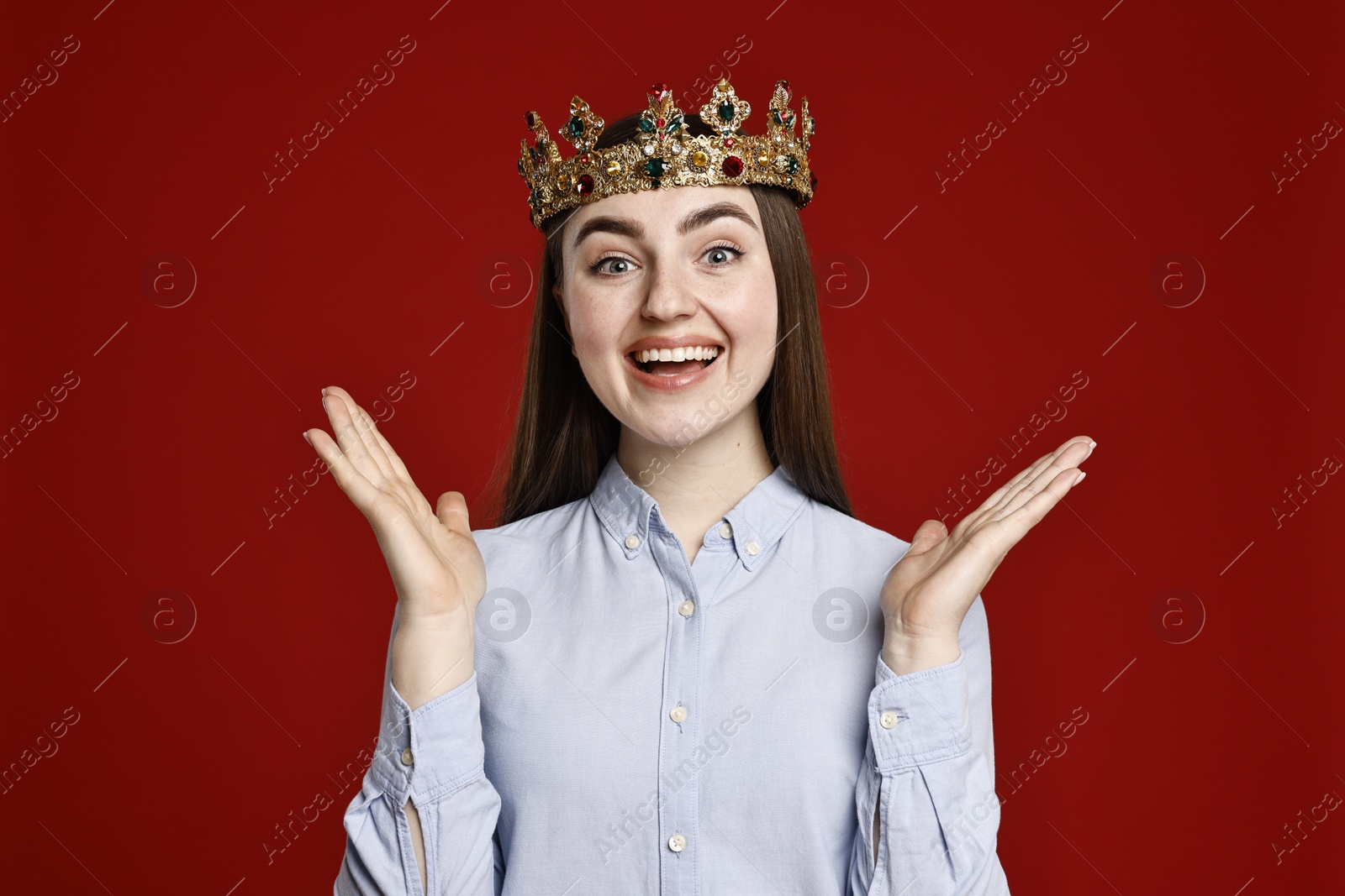 Photo of Smiling woman in elegant crown on dark red background