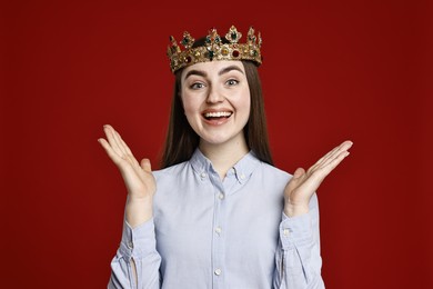 Photo of Smiling woman in elegant crown on dark red background